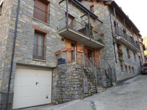 a stone building with two garage doors and a balcony at Apartamentos Nilsson, Casa Botigue, centro de Plan in Plan +8 photos