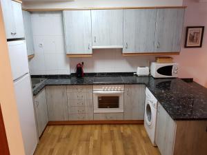 a kitchen with white cabinets and a black counter top at Apartamentos Nilsson, Casa Botigue, centro de Plan in Plan