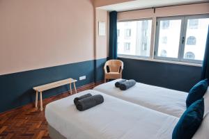 two beds in a room with a chair and window at Portos Wine, Divine Apartment 2B in Lisbon