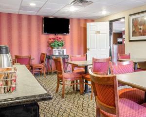 a restaurant with tables and chairs and a tv on the wall at Quality Inn Broken Arrow - Tulsa in Broken Arrow