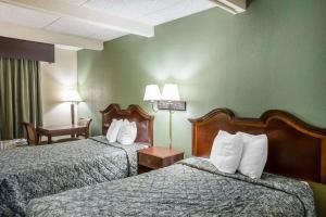 Habitación de hotel con 2 camas, silla y mesa en Rodeway Inn, en Laurens