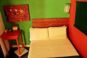 a small bedroom with a bed and a red and green wall at Art Hotel Aos Sinos Dos Anjos in Arraial d'Ajuda