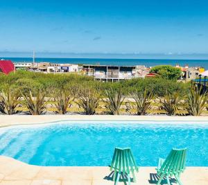two green chairs sitting next to a swimming pool at Unique Hotel & Suites in Punta Del Diablo