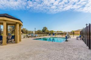 - une piscine avec un pavillon à côté d'une clôture dans l'établissement Comfort Suites, à Channelview