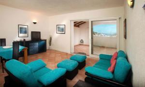 un soggiorno con sedie blu e TV di Trilocale Vignamarina a Santa Teresa di Gallura