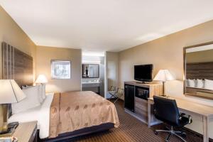 a hotel room with a bed and a desk and a television at Quality Inn Paris Texas in Paris