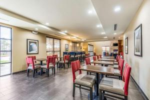 um restaurante com cadeiras vermelhas, mesas e janelas em Comfort Suites em Channelview