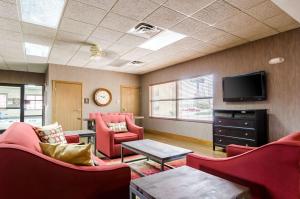 a waiting room with red chairs and a flat screen tv at Comfort Inn in Colby