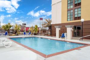 une piscine dans un hôtel avec des chaises et un bâtiment dans l'établissement Comfort Inn & Suites Biloxi-D'Iberville, à Biloxi