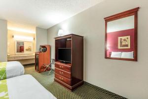 a hotel room with a bedroom with a bed and a mirror at Rodeway Inn Prattville I-65 in Prattville