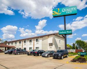 a sign for a hotel with cars parked in a parking lot at Quality Inn near I-72 and Hwy 51 in Forsyth