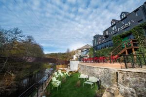 a hotel with a balcony with chairs and a river at Hotel Val de Poix in Saint-Hubert