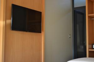 a flat screen tv on the wall of a bedroom at Hotel Tomaso in Chivilcoy