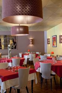 un restaurante con mesas y sillas rojas y blancas en Hôtel et Résidence des Bains, en Vic-sur-Cère