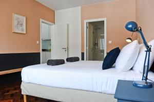 a bedroom with a white bed with a blue lamp at Gin o clock Apartment 3A in Lisbon