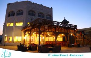 a large building with a balcony and tables and chairs at El Hayah Resort - Families Only in Ain Sokhna