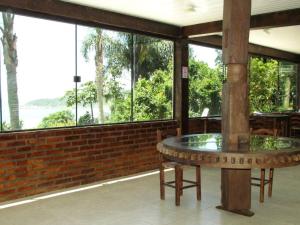 a room with a table in a building with windows at Pousada Estação Baleia in Praia do Rosa