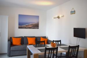 een woonkamer met een bank en een tafel met oranje kussens bij ALCALDE MARCIAL SANCHEZ VELAZQUEZ 15 in Caleta De Fuste