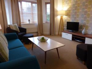 a living room with a blue couch and a coffee table at Basingstoke Apartments - St Raphael House, City Centre Charming Apartments in Basingstoke +4 photos