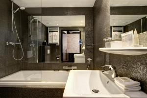 a bathroom with a tub and a sink and a bath tub at The Pavilions Amsterdam, The Toren in Amsterdam