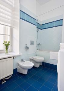 a blue tiled bathroom with a toilet and a sink at ReHouse- Didzioji 39 in Vilnius