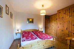 ソラーガにあるAgritur Ciasa Dò Parèのベッドルーム1室(木製ベッド1台、赤い枕付)