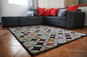 sala de estar con sofá y alfombra en Butterfly Apartments en Livingstone