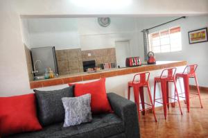 salon z kanapą i czerwonymi stołkami w obiekcie Butterfly Apartments w mieście Livingstone