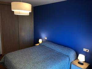 niebieska sypialnia z łóżkiem i 2 lampami w obiekcie Costa Da Morte Deluxe w mieście Malpica