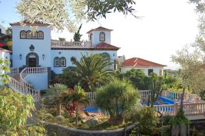 a large white house with a swimming pool and trees at Quinta da Paz in Caniço