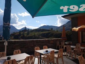 a patio with tables and chairs and a view of mountains at Hotel Simplon-Blick in Simplon Hospiz