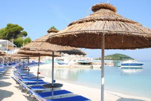 a group of beach chairs and umbrellas on a beach at Guesthouse Dollomaja Ksamil in Ksamil