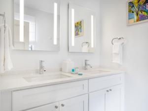a white bathroom with two sinks and two mirrors at Beach View Hotel in Saint James