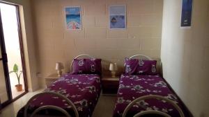 2 camas en una habitación con sábanas moradas y una mesa en Rubis, en Victoria