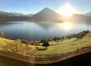 uma vista para uma massa de água com o pôr do sol em CHALET EGGLEN "Typical Swiss House, Best Views, Private Jacuzzi" em Sigriswil