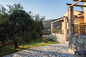 a stone walkway next to a house with a tree at Villa Manos in Kalamitsi Amygdali