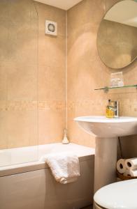 a bathroom with a sink and a tub and a mirror at Cotswold Place in Cirencester