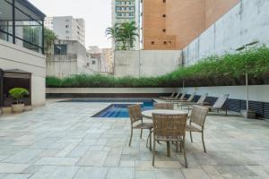 une terrasse avec une table, des chaises et une piscine dans l'établissement BHomy Jardins Conforto na Alameda Lorena TU705, à São Paulo