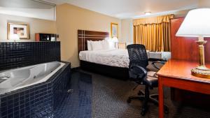 een hotelkamer met een bed, een bureau en een bad bij Rancho San Diego Inn & Suites in El Cajon
