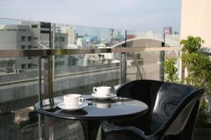 uma mesa e cadeiras com chávenas e pires numa varanda em Baiyoke Boutique Hotel em Bangkok