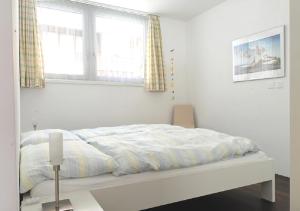 ツェルマットにあるApartment Topasの白いベッドルーム(ベッド1台、窓2つ付)