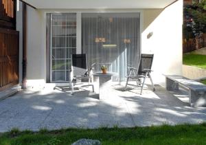een patio met 2 stoelen, een tafel en een bank bij Apartment Topas in Zermatt