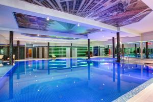 - une grande piscine dans un bâtiment doté d'un plafond dans l'établissement Sunflow Park Hotel, à Kartmazovo