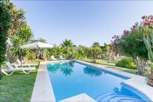 a swimming pool in a yard with a chair and trees at Villa Aurelia Sea views Heatable Pool - Billiard Ping-pong Fooball table - Beach & All at 500 m in La Cala de Mijas