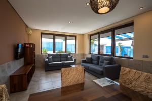 un salon avec des canapés et une télévision à écran plat dans l'établissement El Caseron de Conil & Spa, à Conil de la Frontera