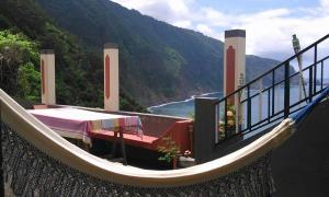 a hammock on a balcony with a view of the ocean at Janela para o Atlântico in Porto Moniz