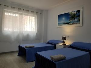 アリカンテにあるAvenida de Denia N11 close to the Beachのベッド3台(青いシーツ付)、窓が備わる客室です。