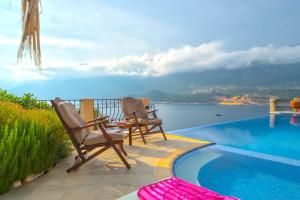 - deux chaises et une table à côté de la piscine dans l'établissement Villa Poseidon-in winter heated outdoor pool, à Kaş