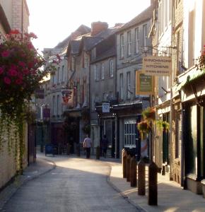 a street in a town with buildings and people walking down the street at Cotswold Place in Cirencester