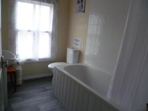 a bathroom with a tub and a toilet and a window at Gilmore House in Ardglass +23 photos